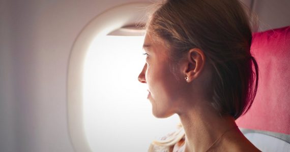 Flight hacks - Woman sitting on chair looking outside window on plane.
